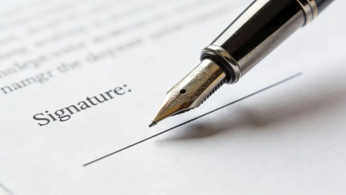 A luxurious fountain pen poised to sign a legal document on a blank signature line.
