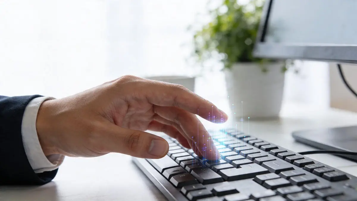 A professional typing on a keyboard with digital data visualization graphics overlaying the keys